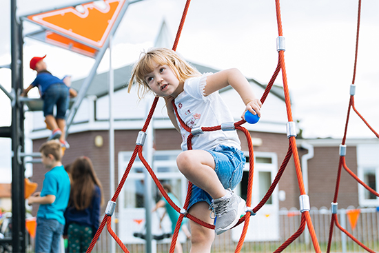 girl climbing up a playground rope net